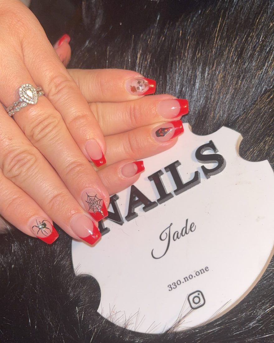 Red french tips with silver spiderweb art on the accent nails